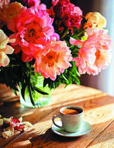 Чашка ароматного кофе и букет пионов в солнечных лучах