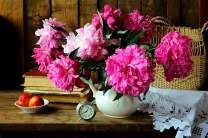 Розовые пионы в белой вазе и персики на столе